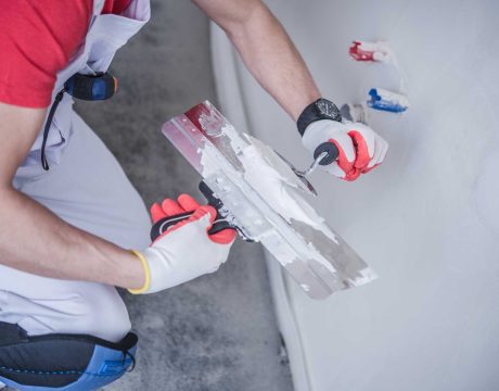 Drywall Patching Job. Apartment Remodeling. Caucasian Construction Worker with Patching Material and Tools.